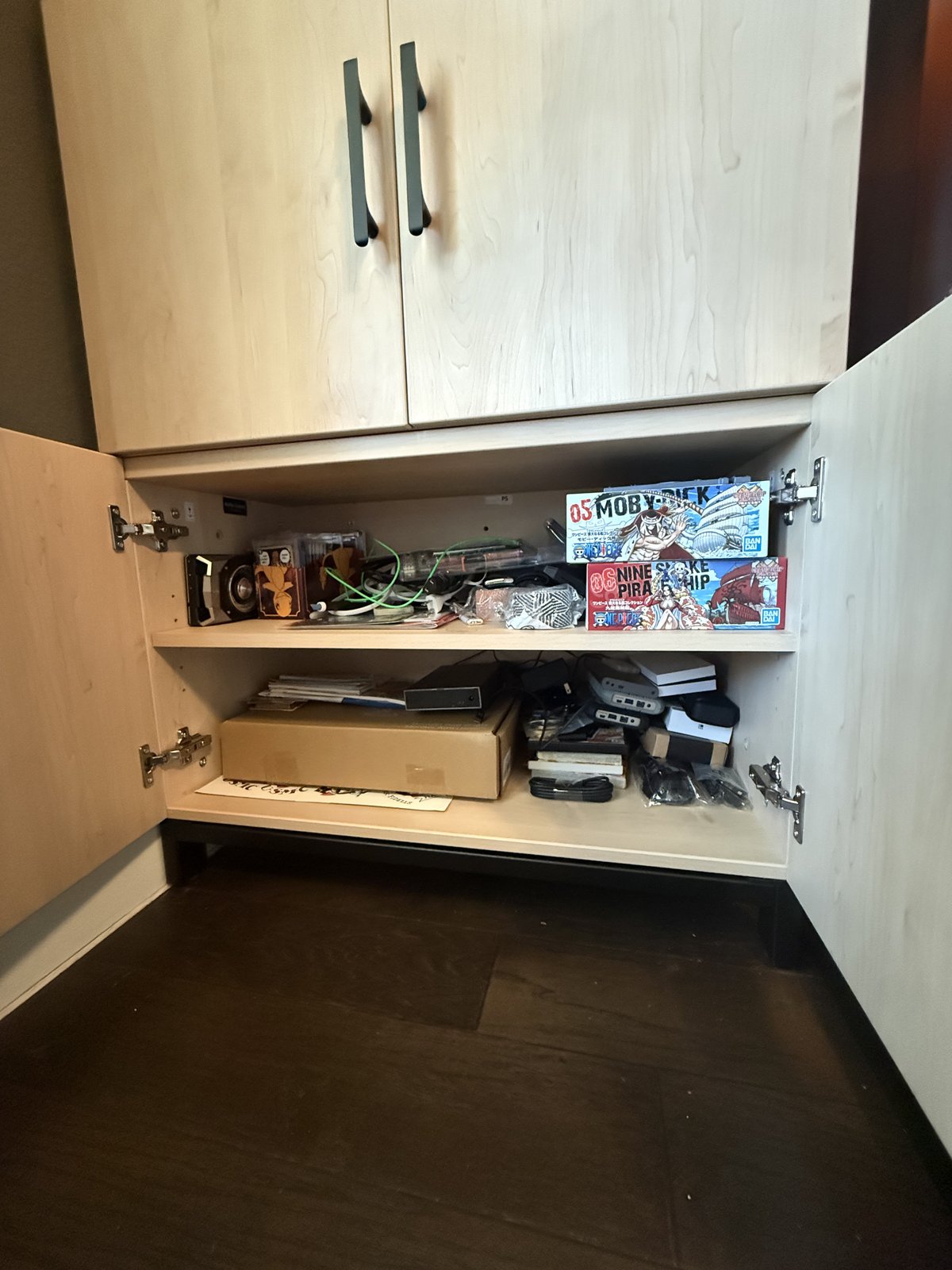 The bottom MoPac cabinet with its doors open, showing cables, boxes, and One Piece model kits on two levels