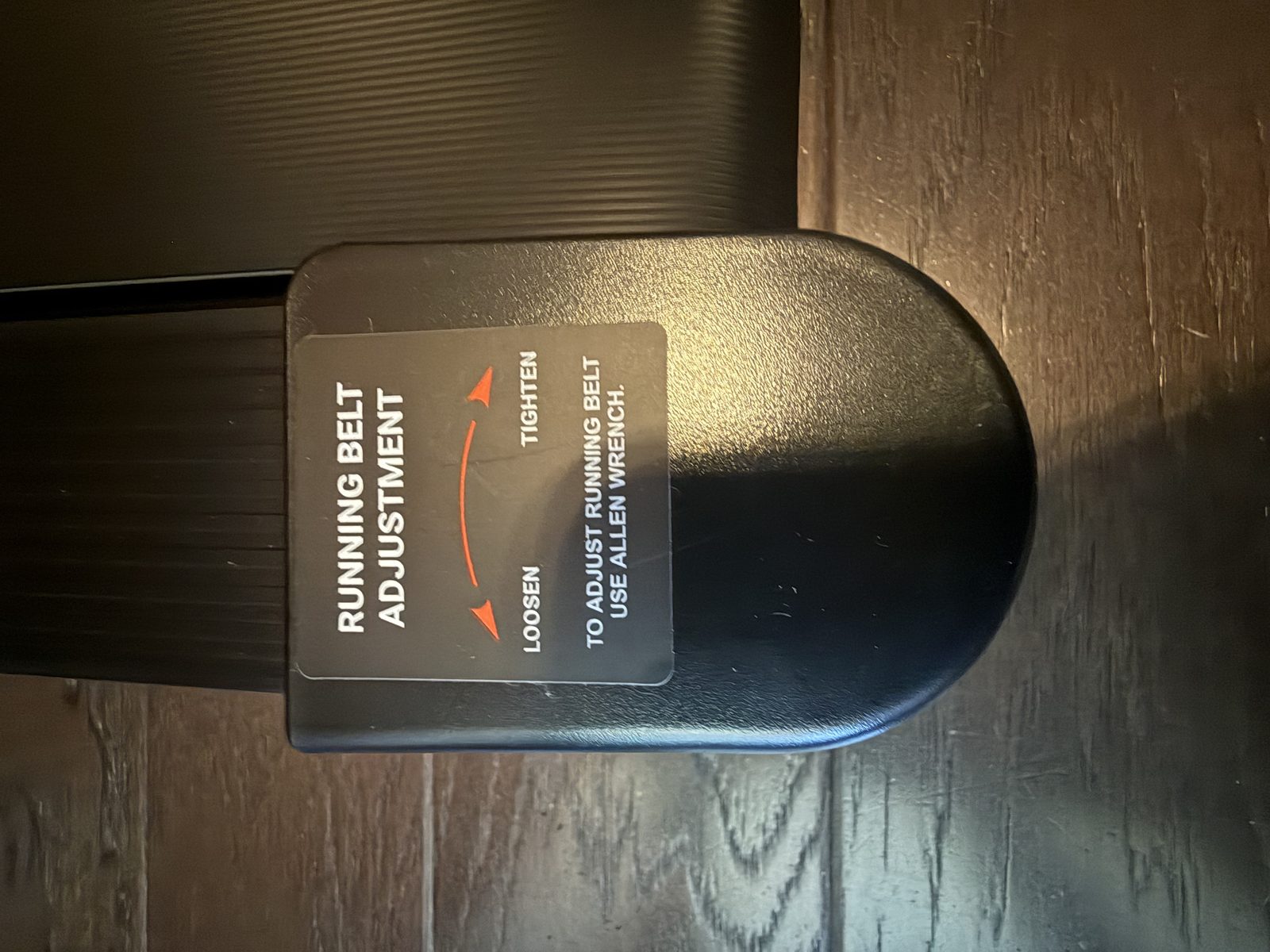 The belt adjustment sticker and Allen bolt points on the back of the walking pad